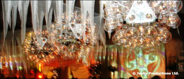 Hanging mirror balls and white streamers lit in orange above a bar area