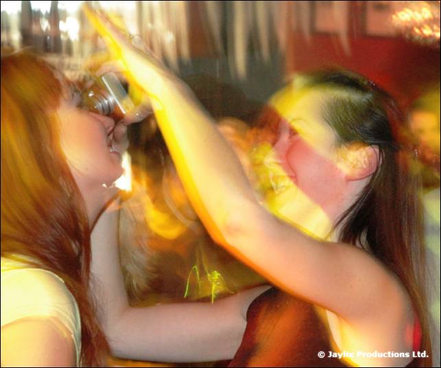 Blurred close-up of two people dancing, one tipping a drink to her mouth
