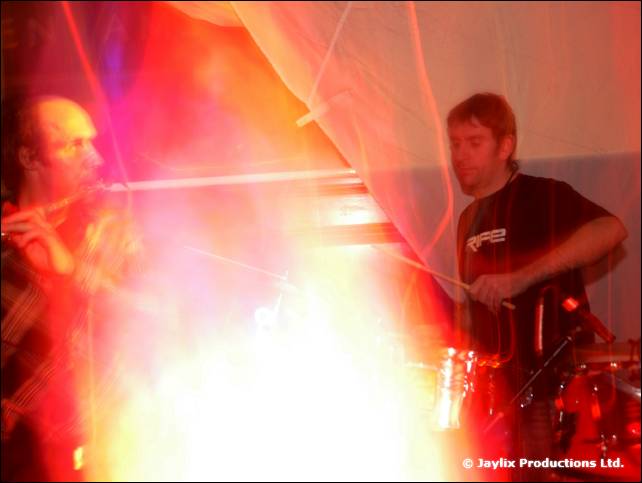 Blurred bright orange and white light flare with a drummer and another person playing a flute