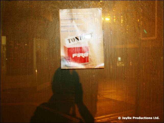 A poster reading Tonight with a FIRE logo on a rain streaked window, with a dark reflection below