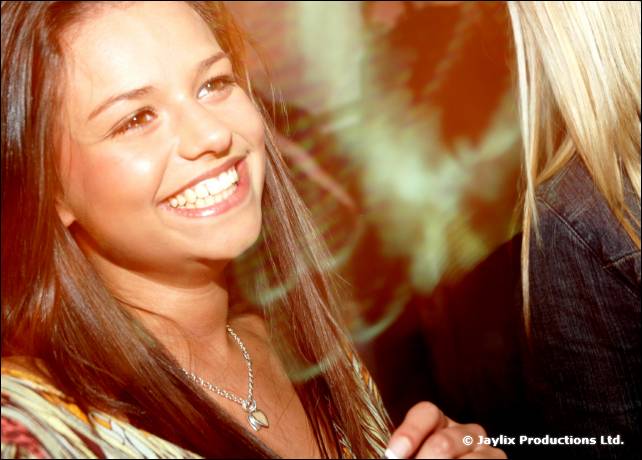 A smiling woman with long dark hair and a pendant necklace