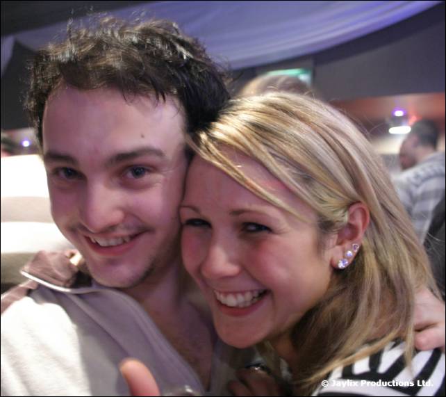 A smiling man and a woman with blonde hair lean their heads together