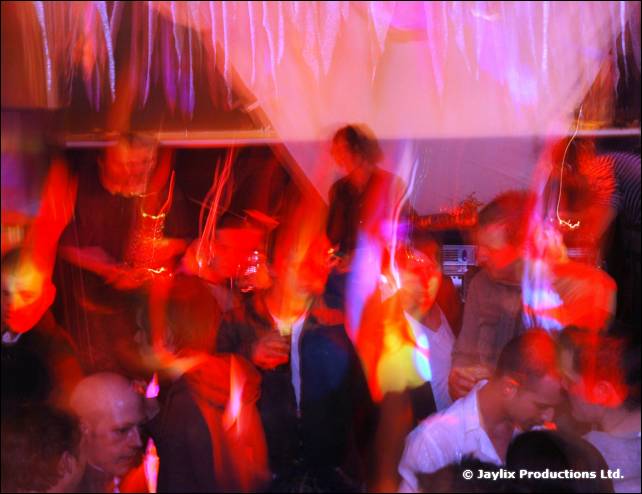 Blurred dancers in red and pink light beneath hanging fabric