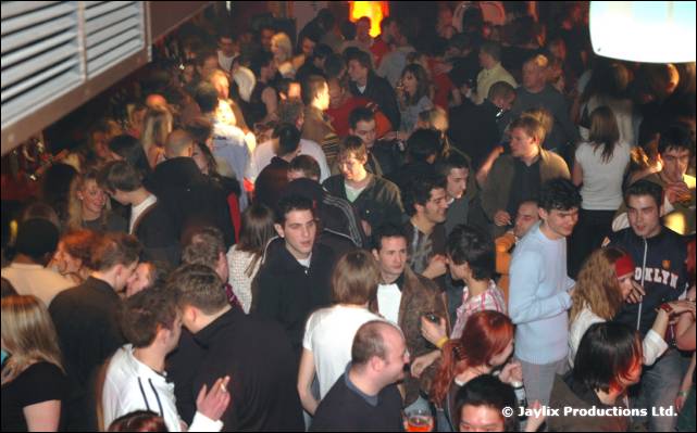 A packed crowd of people standing in a dim bar