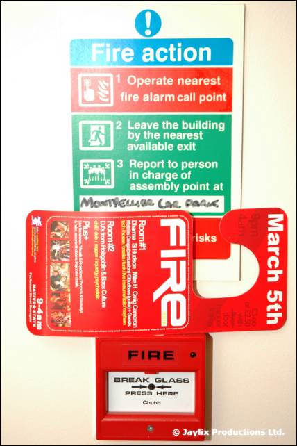 A red FIRE door hanger dated March 5th hangs over a fire alarm call point and a Fire action notice