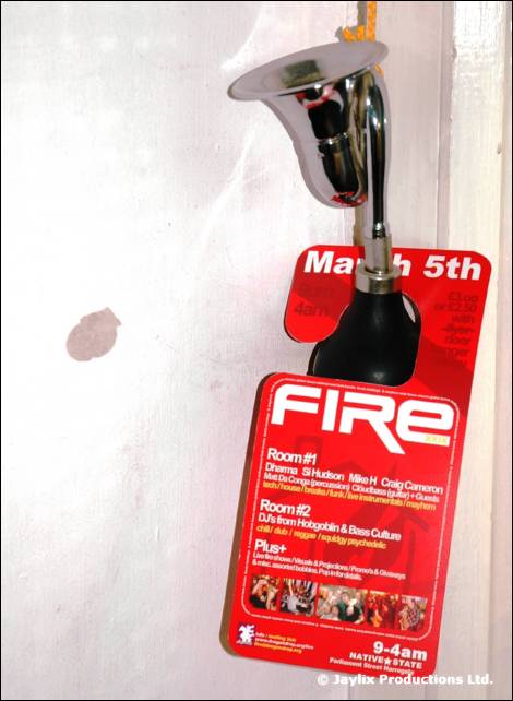 A red FIRE door hanger dated March 5th hangs from a silver handle on a white wall