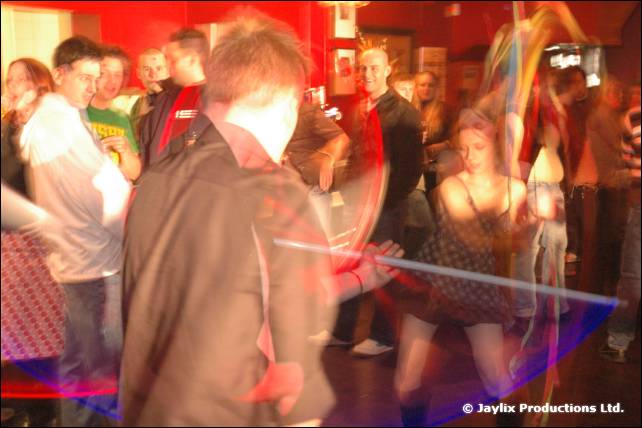 A blurred dance floor with people dancing and a light trail across the image