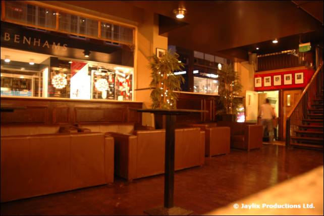 An empty bar lounge with leather sofas and a shop front in the background