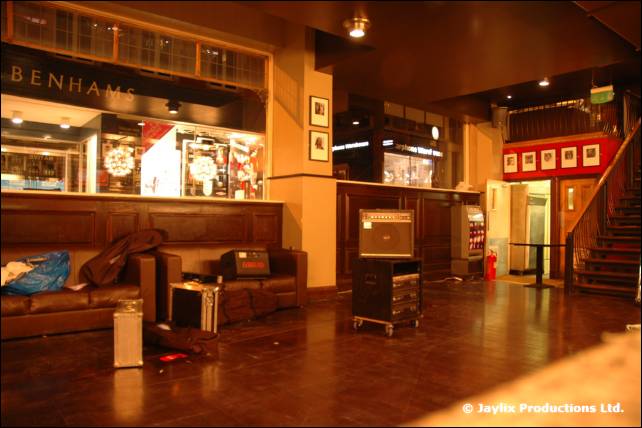 A bar lounge with a few bags and amplifiers on the sofas and floor, before a night begins