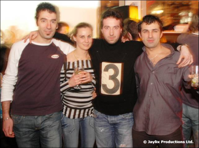 Three men and a woman hold a wine glass and pose with their arms round each other, one wearing a number 3 on his top