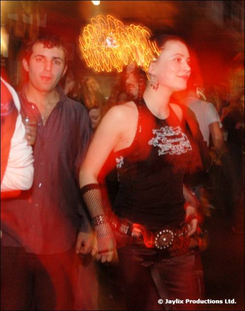 A woman in a black top and a man in a blue shirt dance, with an orange light streak above