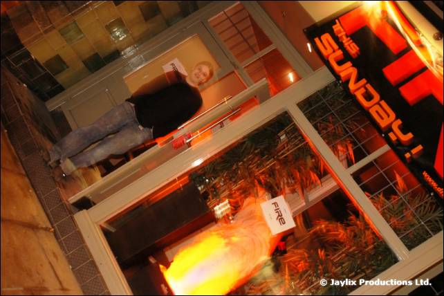 A shop front at night with a sign reading Sunday and a small FIRE flyer in the window