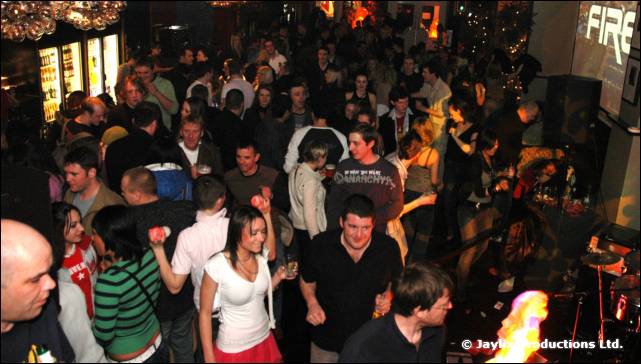 A view from above of a crowded bar, with a FIRE sign at the top right and a flare at the bottom right