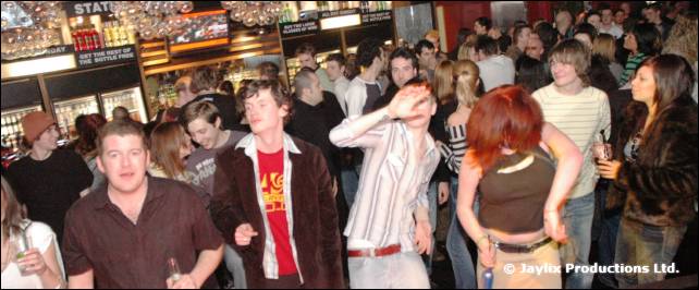 A crowd in a busy bar, with several people dancing in the foreground
