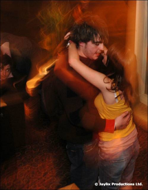 A man and a woman in a yellow top embrace and dance, blurred by movement