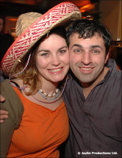 A woman in a straw sombrero and a man in a grey shirt smile together