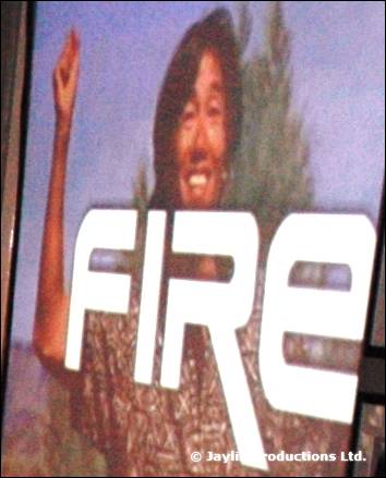 A large FIRE logo on a projected image of a smiling person with an arm raised