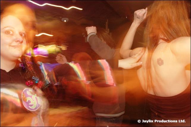 Dancers in a blurred, orange lit room, a woman on the left and a person with bare shoulders on the right