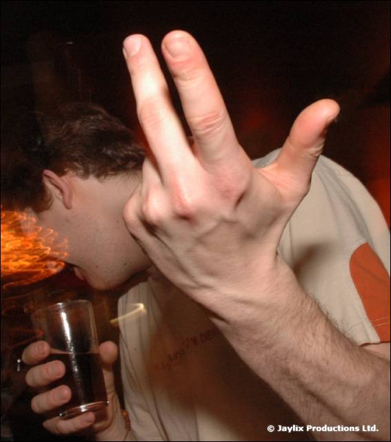 A blurred close-up of a hand held in front of a person drinking from a glass