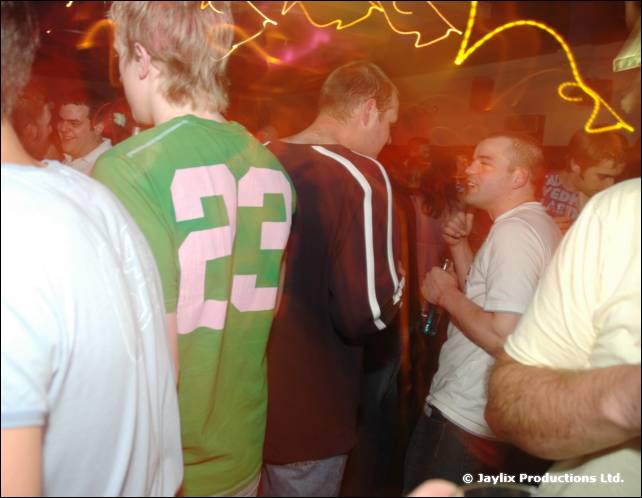 People in a crowded bar, one wearing a green shirt with the number 23