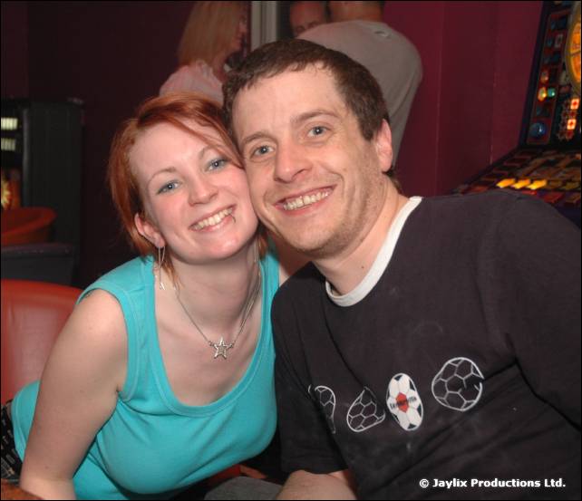 A woman in a teal top and a man in a dark t-shirt pose cheek to cheek
