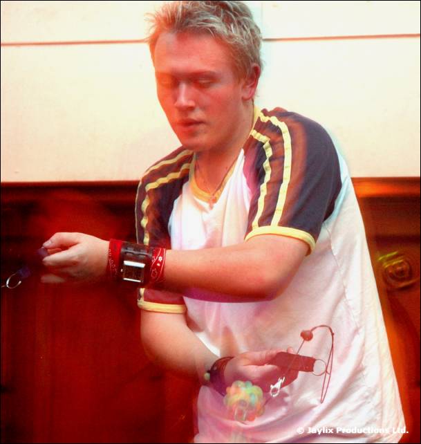 A young man with blond hair in a sports style top looks down, wearing wristbands