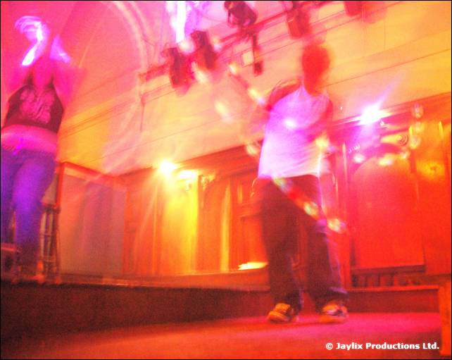 Blurred figures on a stage under bright pink and purple lights