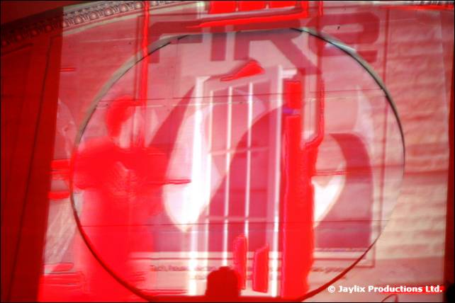 A red projection of the FIRE logo with a circular frame on a wall