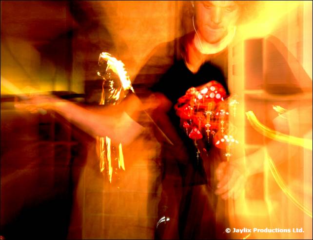 A heavily blurred person in black holds something red in orange light