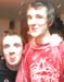 Very small image of two people posing, one in a red top