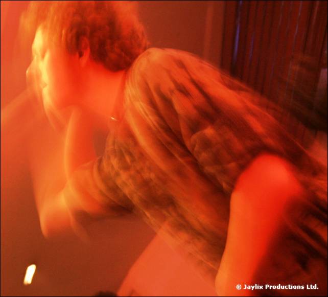 A heavily blurred person in a checked shirt in orange light