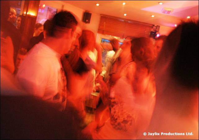 Blurred people dancing in a bar, with orange and red light