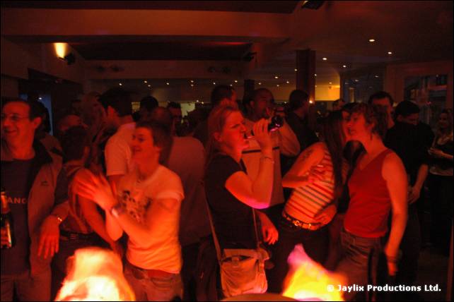A dark, crowded bar with people dancing and talking