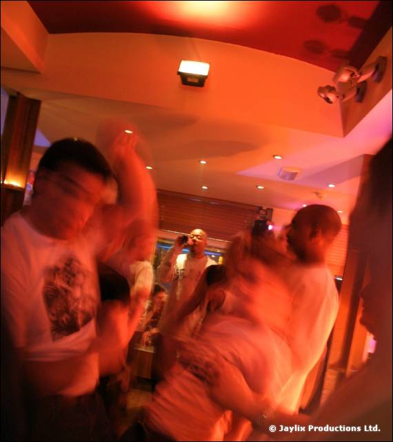 Blurred people dance close together in a bar, with orange light