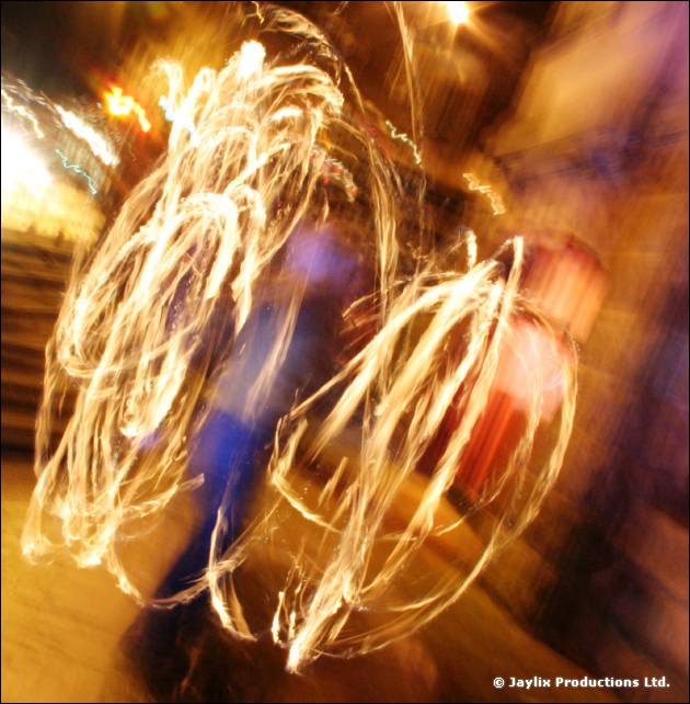 Looping fire trails and blur from a person spinning poi at night