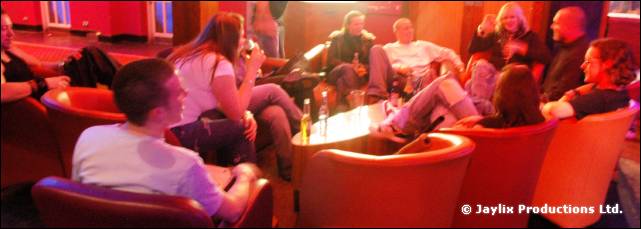 People sit and talk on red armchairs around a low table in a lounge area