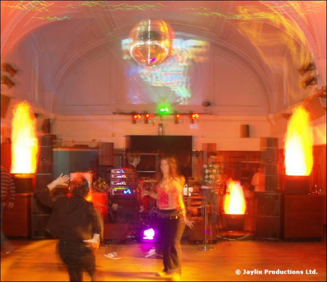 A vaulted hall with a mirror ball, two flame effects and two people dancing on the floor