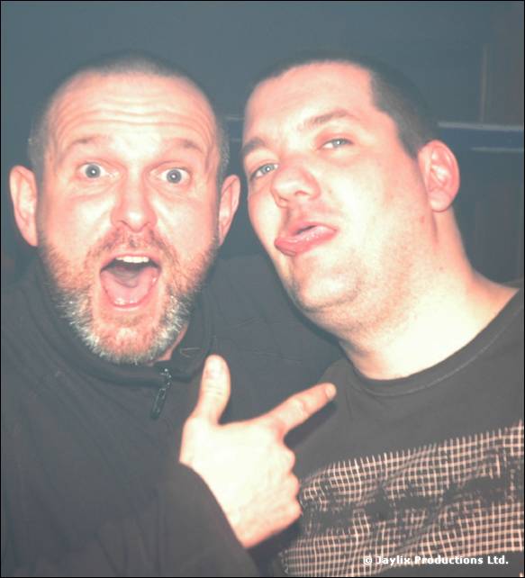 Two men pull faces for the camera, one with his mouth open and pointing, the other sticking out his tongue