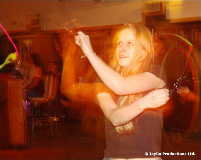 A person with long hair dances holding a cord prop, blurred with motion