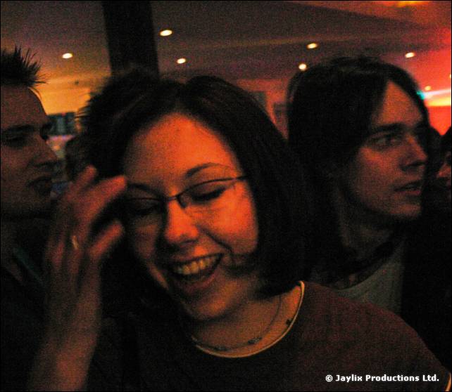 A woman with glasses laughs with her head down, two dark-haired men beside her