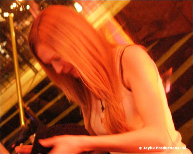 A woman with long hair looks down in orange light