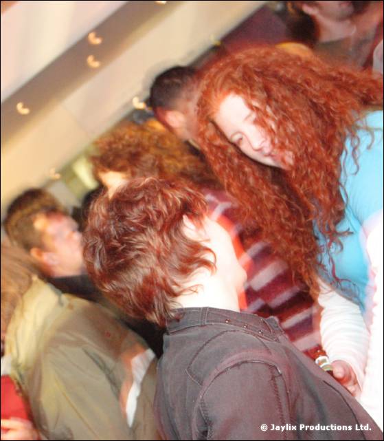 Dancers blurred by motion, a woman with long curly red hair in the centre