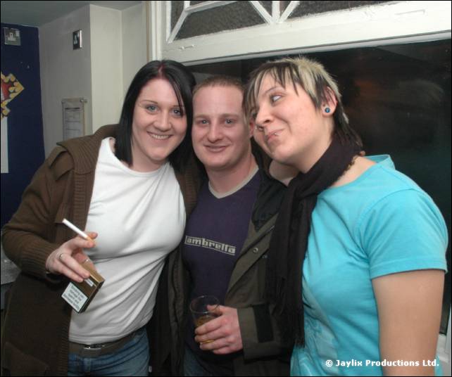 A woman in a white top, a man in a navy top and a person in a pale blue top pose together