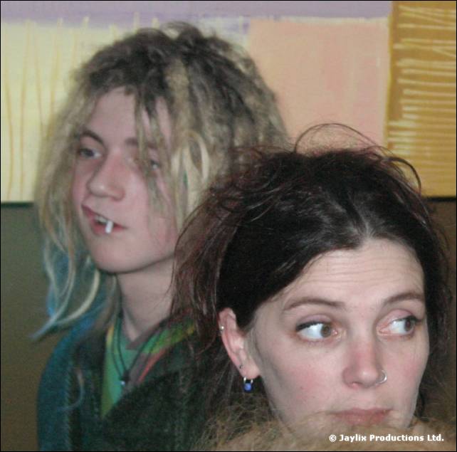A young person with blonde dreadlocks and a woman with dark hair look to the side