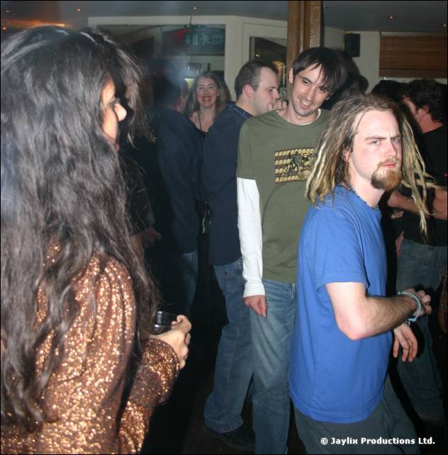 People in a bar, a man with blond dreadlocks in a blue T-shirt and a woman in a sparkly top