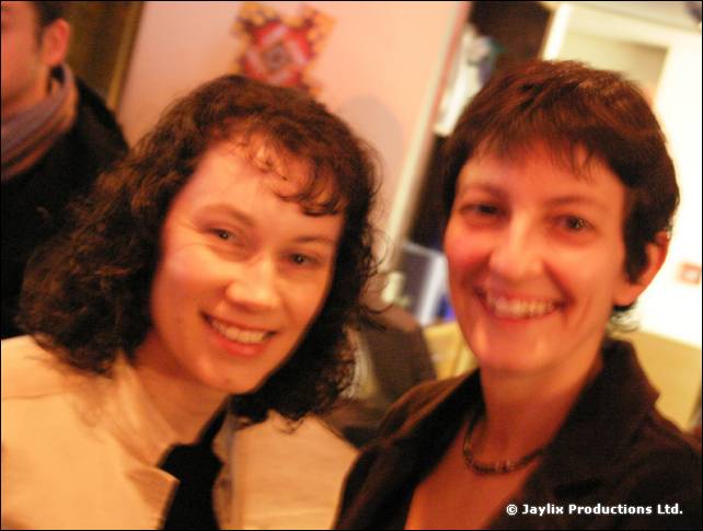 Two smiling women with dark curly hair lean together