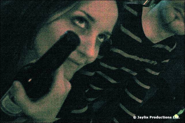 A dark, grainy image of a woman holding a bottle in front of her face