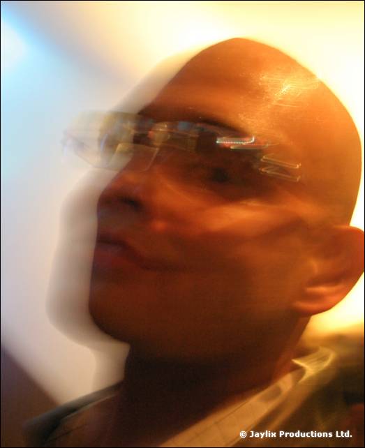 A blurred close-up of a bald man wearing glasses, face smeared by motion