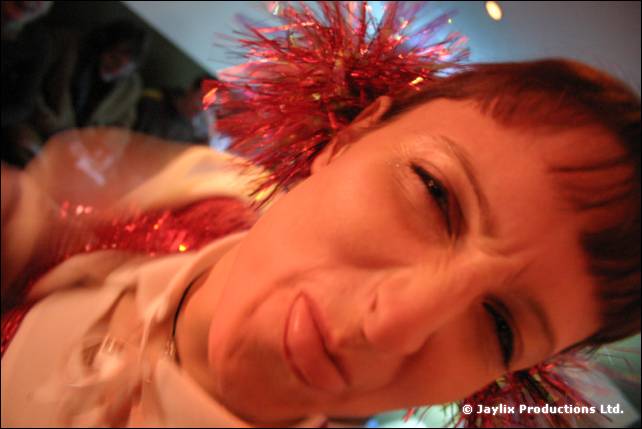 A tilted close-up of a woman with a red tinsel hair decoration looking at the camera