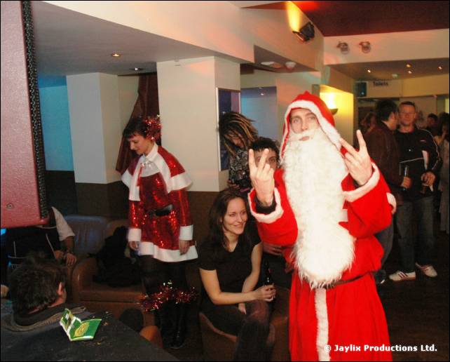 A person in a Father Christmas costume makes a hand gesture next to a person in a sparkly red Christmas outfit